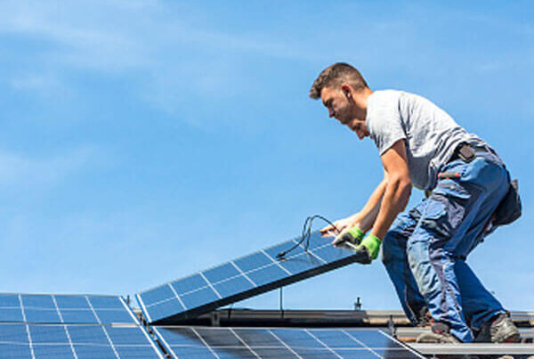 Elektriker montiert Photovoltaikanlage auf einem Dach